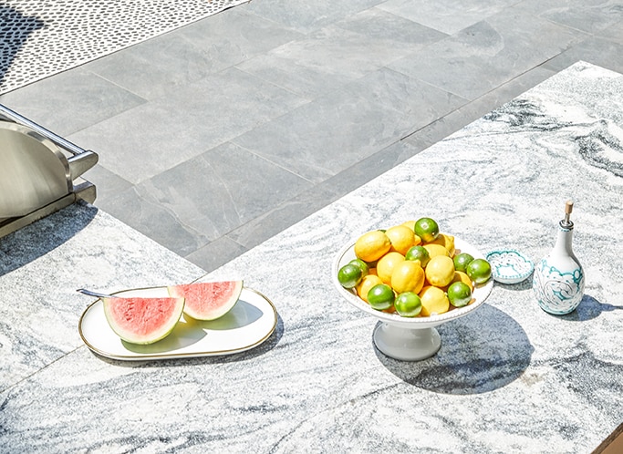 Outdoor bar with white granite countertop and two plates of watermelon, limes, and lemons.