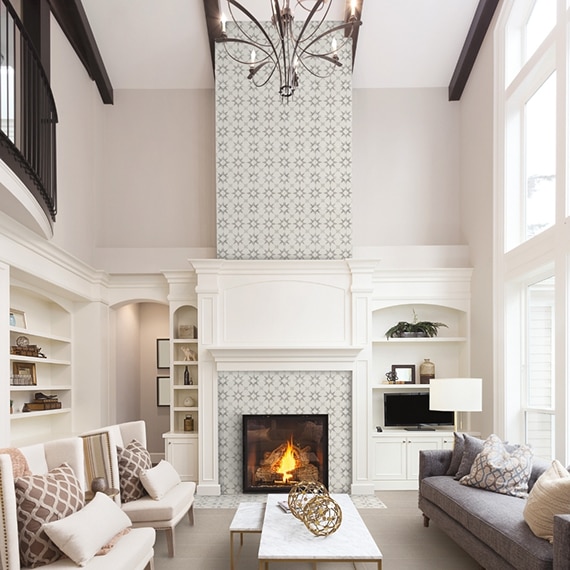 Living room with vaulted ceilings, fireplace with off-white & gray encaustic tile up to the ceiling, white built-ins, and gray stone look flooring tiles.