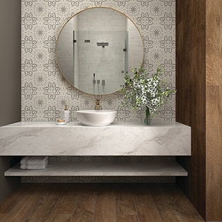 Bathroom vanity with round mirror on a white & gray encaustic tile backsplash, and vessel sink on white quartzite countertop with gray veins.