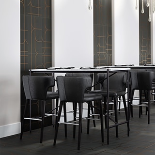 Restaurant dining room with black tile with copper designs on the floor and wall, white seamless slab wall tile, white tables and black leather chairs.
