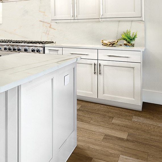 Eat-in kitchen with white & tan quartzite counters, white cabinets, stainless steel gas stove and click tile that looks like wood flooring.
