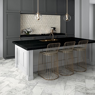 Kitchen with gray marble tile floor, island with black quartzite countertop and built-in copper sink, marble & gold metal diamond-shaped mosaic backsplash, and gray cabinets.