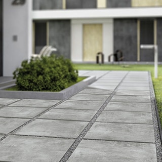 Closeup of gray, stone look, 2CM porcelain pavers set in gray gravel.