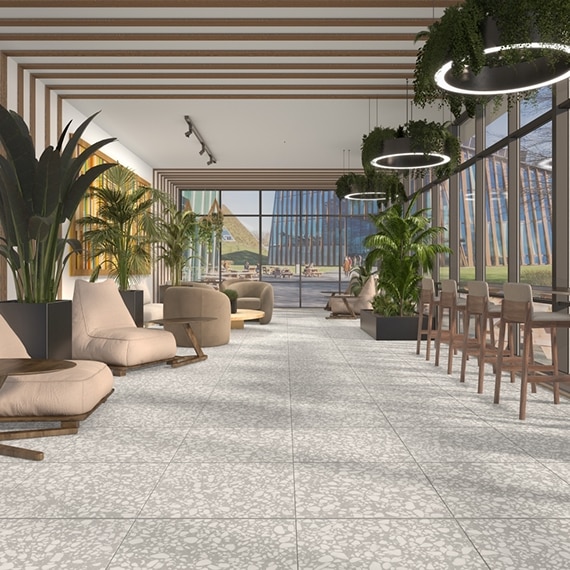 Student center sunroom with gray floor tile that looks like terrazzo, beige over-stuffed chairs with side tables, and beige barstools facing ceiling-to-floor windows.