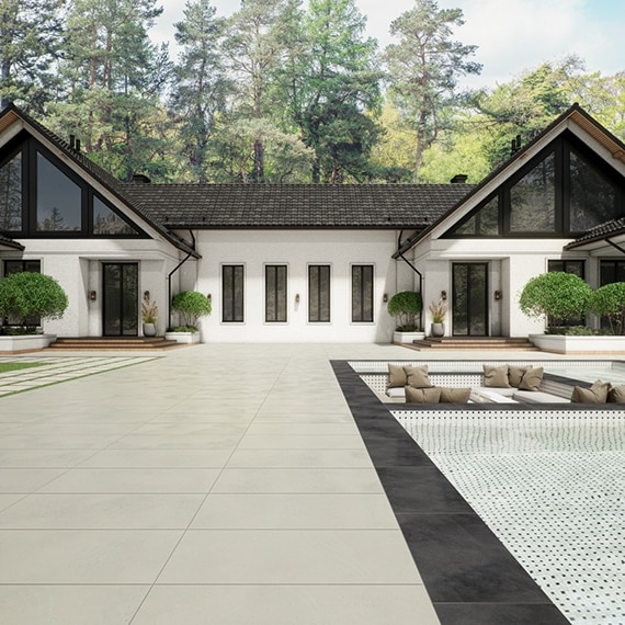 Backyard of a large, white house with a pool containing a sunken seating area next to a large pathway.