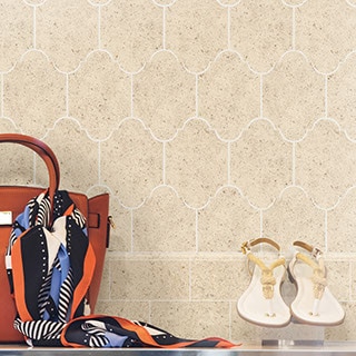 Beige limestone lantern or arabesque shaped mosaic feature wall in a retail store with shoes, bag and scarf in the foreground.