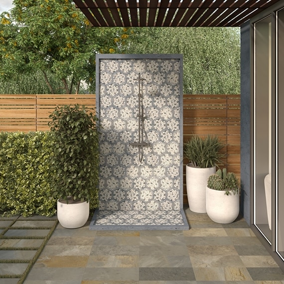 Outdoor shower wall and floor with white & beige pebble mosaic tile with gray hexagon frame, wooden beam patio cover, and multi-color patio floor tile.