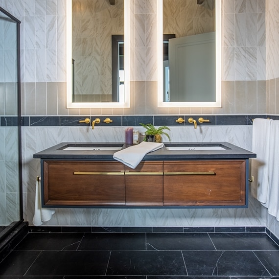 Chip Wade’s residential renovation, Pinhoti Peak, ADU bathroom with black quartz countertop, backsplash of white marble look tile, black marble look tile, and gray wall tile.