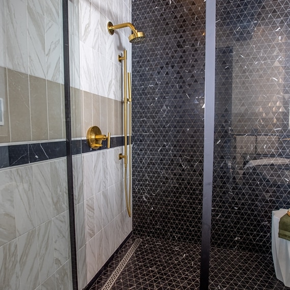 Chip Wade’s residential renovation, Pinhoti Peak, ADU shower wall and shower floor with black marble mosaic tile, white wall tile and gray wall tile that look like marble.