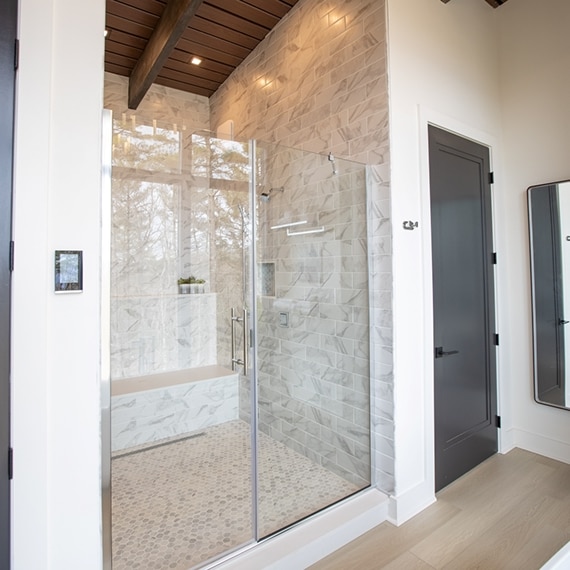 Chip Wade’s residential renovation, Pinhoti Peak, master bathroom shower with white and gray marble look tile and white quartz shower bench and shelving.