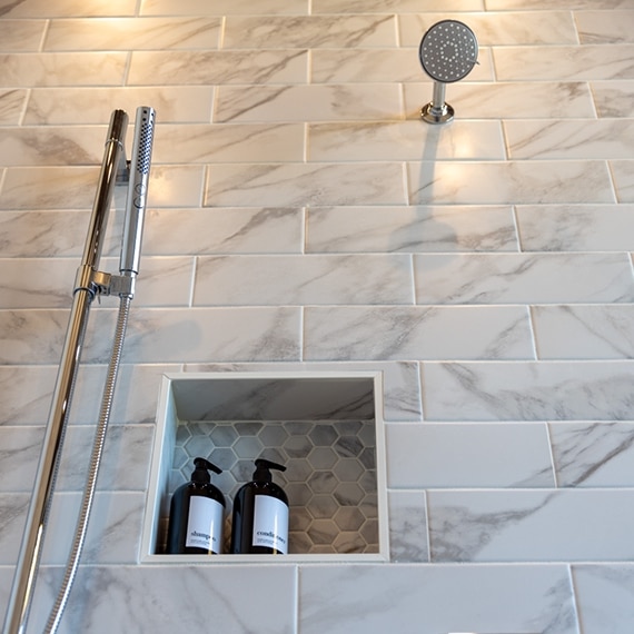 Chip Wade’s residential renovation, Pinhoti Peak, master bathroom shower with white and gray marble look wall tile and penny round tile shower shelf.