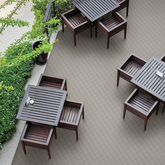 Bird’s eye view of outdoor restaurant with gray 6x6 quarry tile flooring, wood table and chairs, and patio surrounded by shrubs.