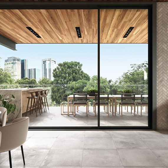 Restaurant indoor and outdoor dining room with gray stone-look floor tile, herringbone wall tile, natural quartzite waterfall island, and view of city skyline.