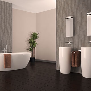 Bathroom with tall ceilings accentuated by pewter metallic-look wall tile arranged in a vertical pattern, dark brown floor tile, soaker tub and two pedestal vanities.