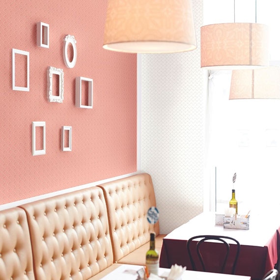 Restaurant booth next to window with peach leather seatback, white mosaic wall tile, and white picture frames on peach mosaic wall tile.