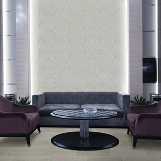 Hotel lobby with feature wall of white diamond-shaped textured tile and inset backlighting, periwinkle velvet couch, purple velvet side chairs and black round coffee table.