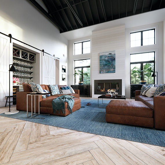 Modern farmhouse living room with herringbone wood look tile flooring, shiplap look porcelain fireplace and black metal vaulted ceiling.