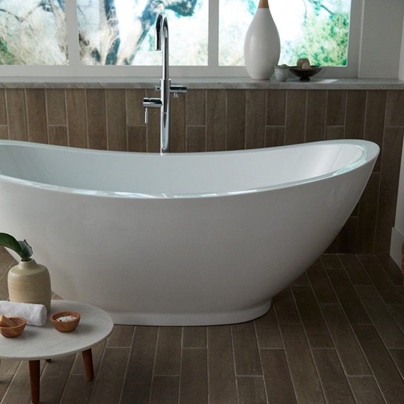 Bathroom with free-standing bathtub in front of picture window, polished silver faucet, wall and floor tiles that look like wood.