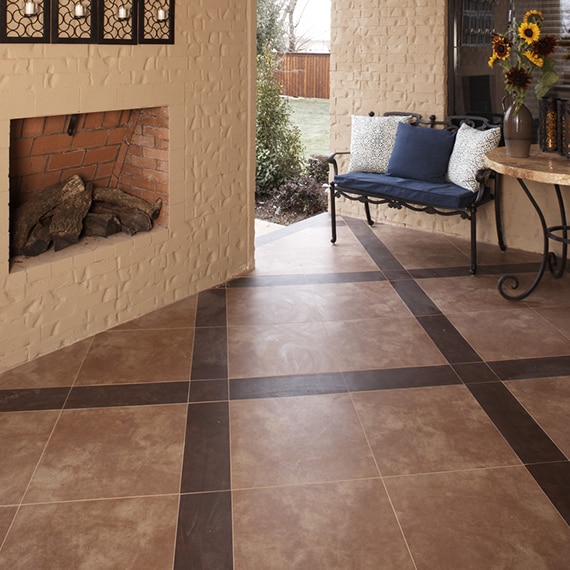 Patio with wood-burning fireplace, dark brown stone look tile and lighter brown stone look tile in a checkered diamond pattern.