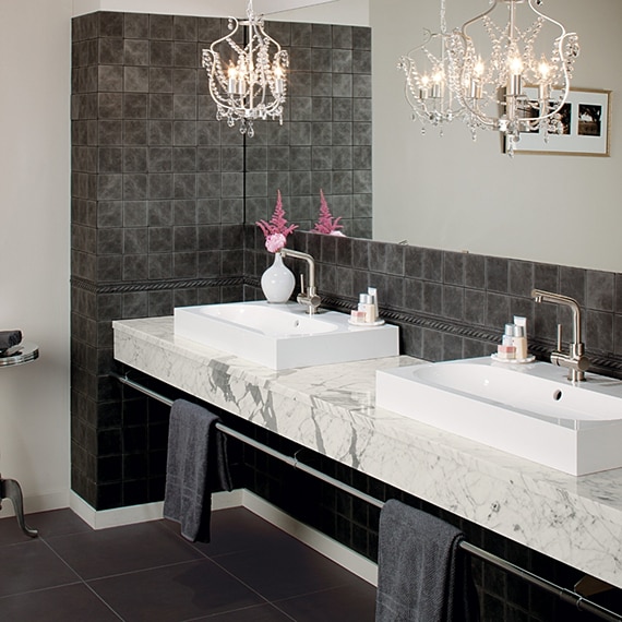 Elegant bathroom white with gray veined marble countertop with dual vessel sinks and crystal chandeliers.