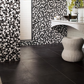Bathroom with white, gray and black mosaic wall tile, white wall tile, glass vessel sink, polished silver faucet, and black floor tile.