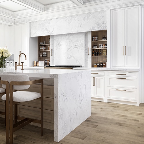 Kitchen with center island, white marble slab on countertops and backsplash, white cabinets, white sitting stools, and wood flooring.