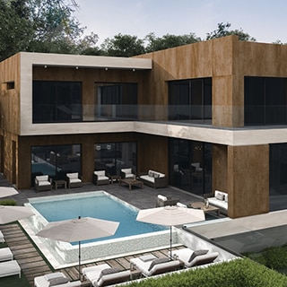 Backyard area of modern two-story house with metallic look cladding, large picture windows, wicker lounge chairs around pool with dark gray stone look tile and wood look paver pool deck.