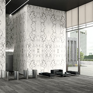 Office building foyer with high ceilings, white & gray bookmatched porcelain slab walls that look like marble, black tile flooring, and floor-to-ceiling windows.