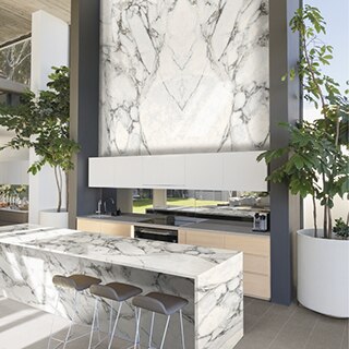 Bookmatched, marble look, porcelain slab backsplash and matching countertop feature white, gray, and beige veining on this wet bar.