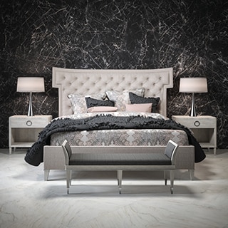Elegant bedroom with white, gray & tan marble look tile flooring, feature wall with black & white marble look, porcelain slab, and cushioned headboard on king-sized bed.