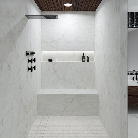 Large open shower with rainfall showerhead, shower walls and bench of white porcelain slab that looks like marble, mosaic shower floor, and matte black fixtures.