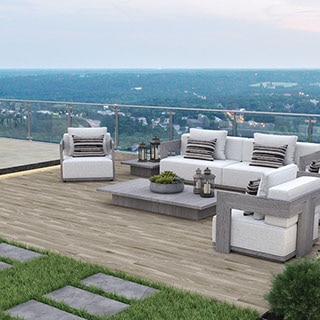 Rooftop patio with a city view, seating area with modern style white and gray furnishings, wood look slip-resistant floor tile, and porcelain paver walkway set in grass.