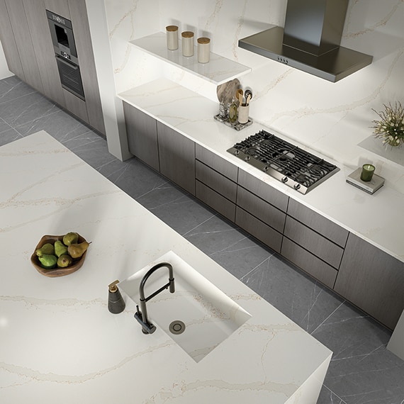 Kitchen with center island, gray cabinets, and white marble look countertops and backsplash.