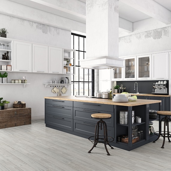 Industrial style kitchen with light gray floor tile that looks like seasoned wood, black island with butcher block countertop, white cabinets, unfinished white walls.