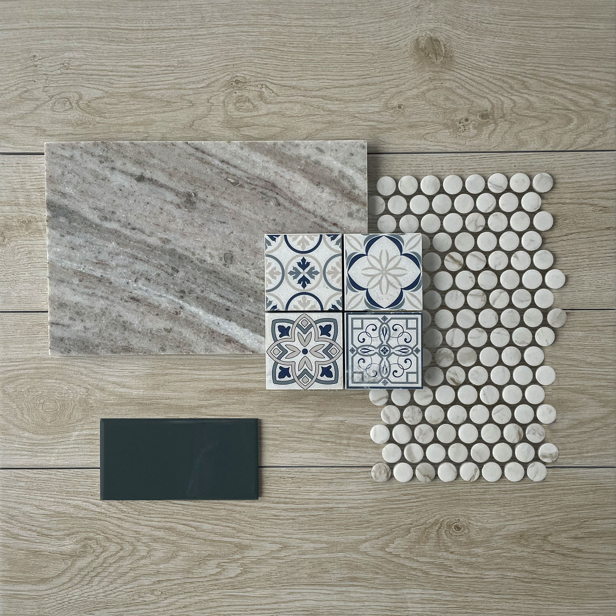 This flatlay contains wood look tile accented by a marble tile, concrete accent tile, marble penny round mosaic, and an encaustic mosaic.