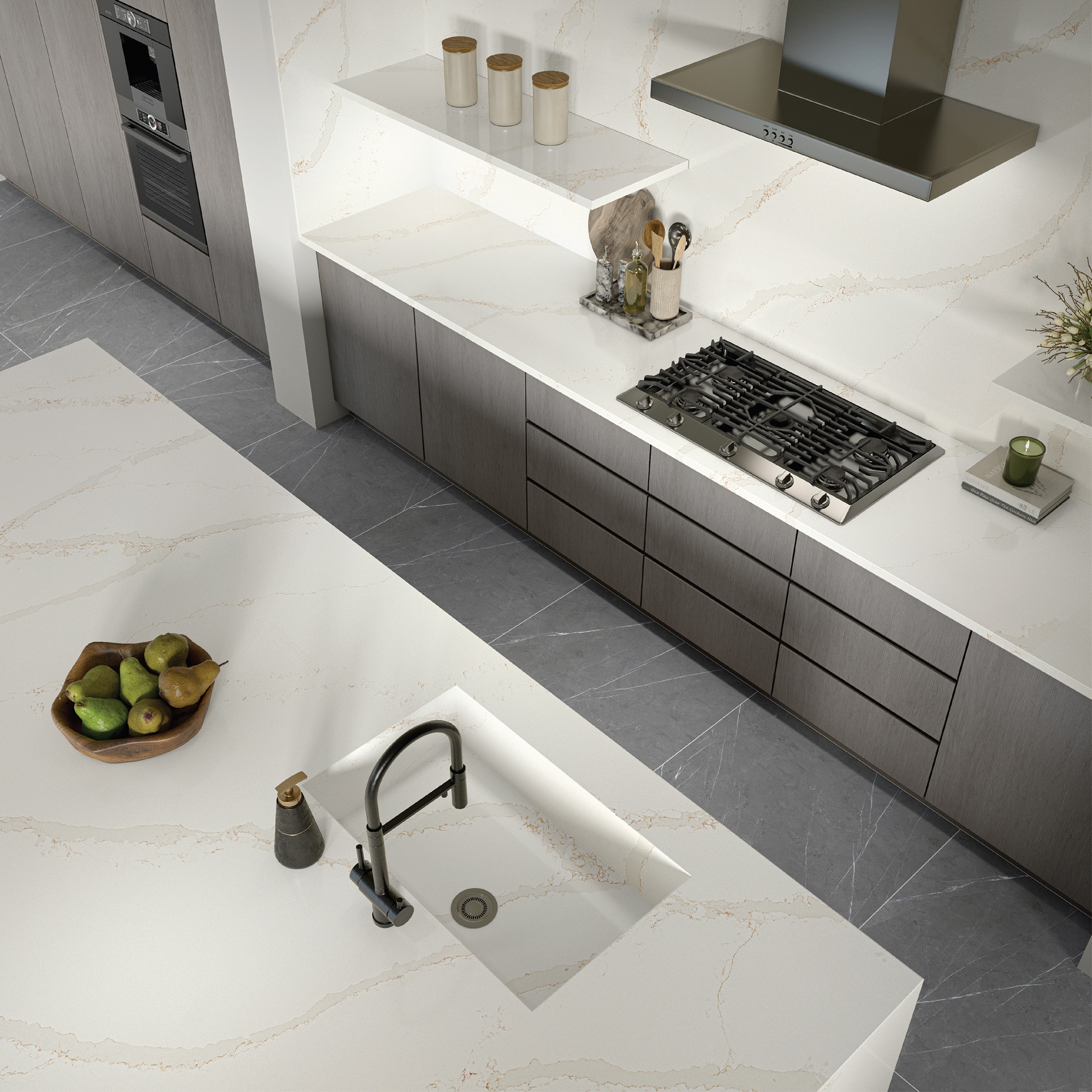 Overhead view of a kitchen with gray stone look floors, gray cabinets, and white marble slab countertops and backsplash.
