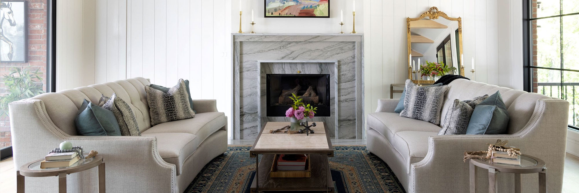 Renovated living room with white vertical shiplap walls, fireplace with gray natural quartzite mantel and hearth, two beige linen sofas with blue & gray pillows.