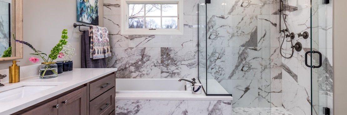 Renovated bathroom featuring white & gray veined porcelain slab that looks marble slab on the wall, tub surround, and shower walls.