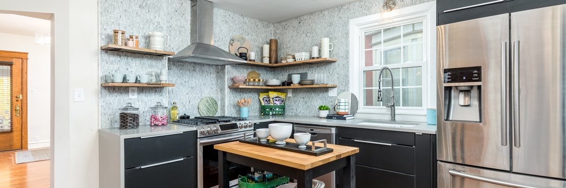 Remodeled farm house kitchen with marble mosaic wall tile, gray quartz countertop, butcher block small island cart, and floating shelves.