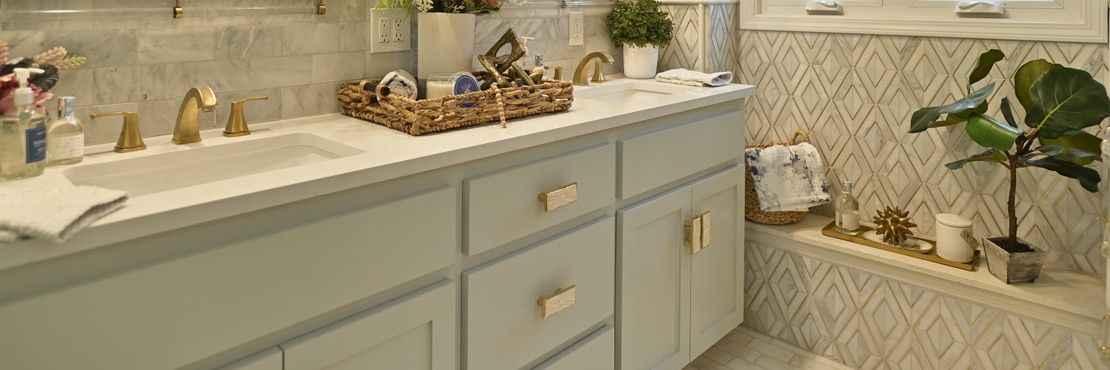 Renovated bathroom with gray marble subway tile backsplash, white quartz vanity countertop & white cabinets, wainscot of gray marble mosaic tile with brass accents.