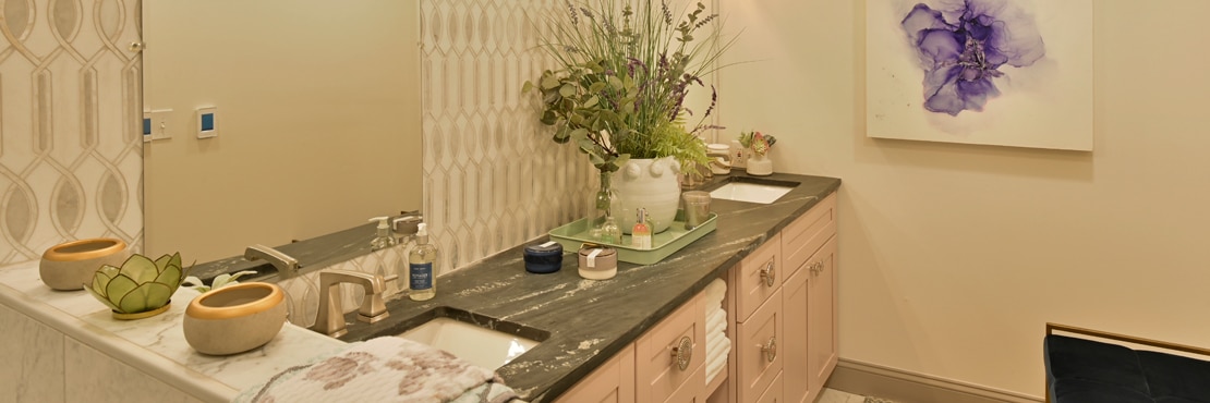 Bathroom with elegant white & gray marble mosaic backsplash with mother of pearl accents, black soapstone vanity counter, and blonde wood cabinets.