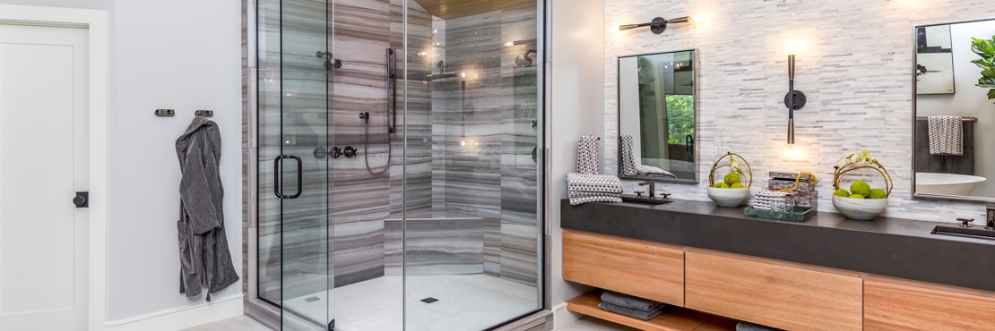 Renovated bathroom with steam shower, brown tile that looks like heavily striated marble, marble mosaic backsplash, and brown quartz vanity countertop.