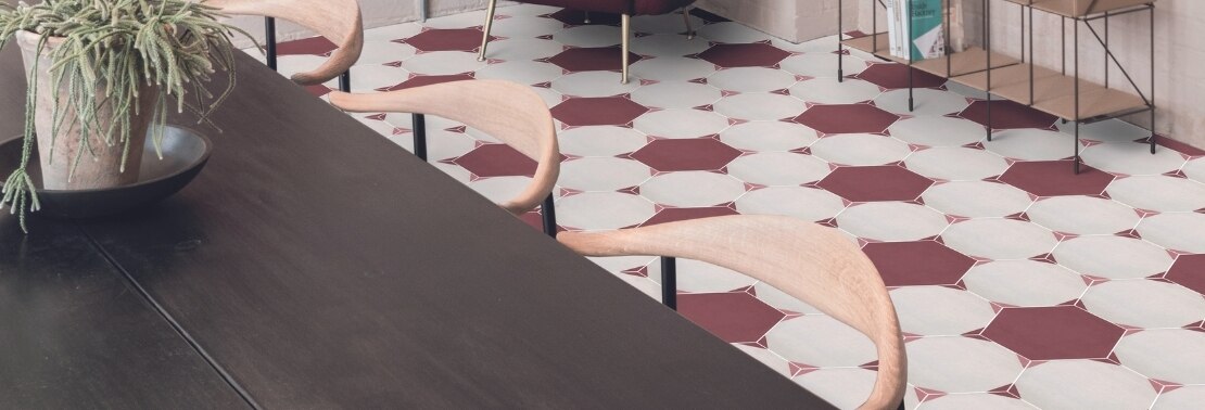 Meeting room with white and maroon hexagon floor tile, dark wood table, light wood chairs, and open shelving with potted plants.