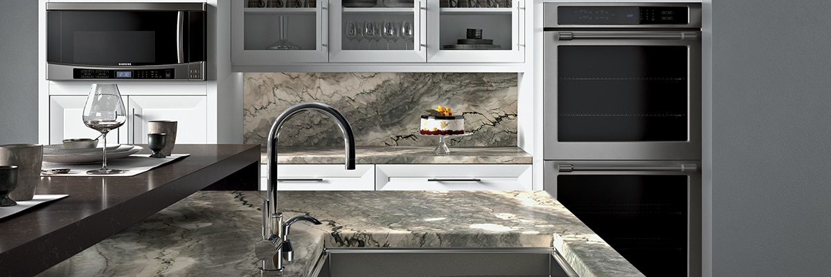 Large kitchen with taupe heavily veined quartzite countertop and backsplash, white open shelving cabinets, island with built-in sink.