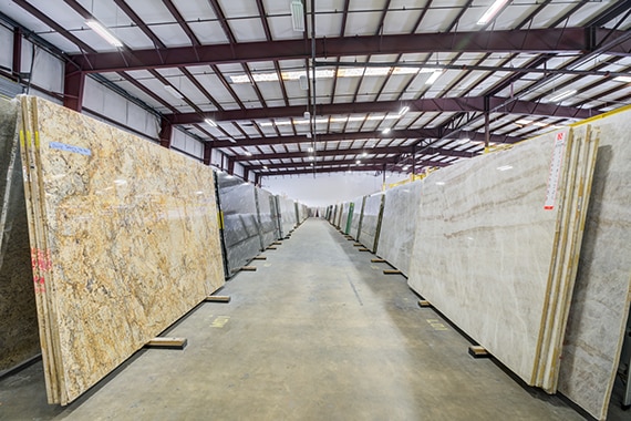 The inside of a Daltile Slab & Stone Center showcasing large granite and quartzite slabs in a row.