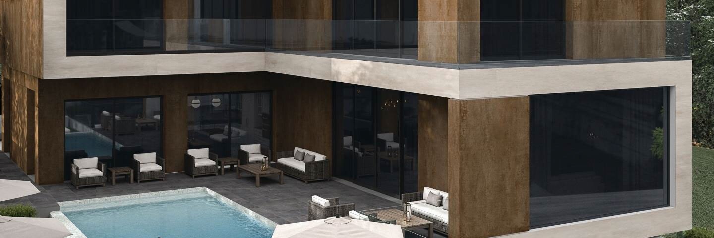 Backyard area of modern two-story hotel with metallic look cladding, large picture windows, wicker lounge chairs around pool with dark gray stone look tile pool deck.
