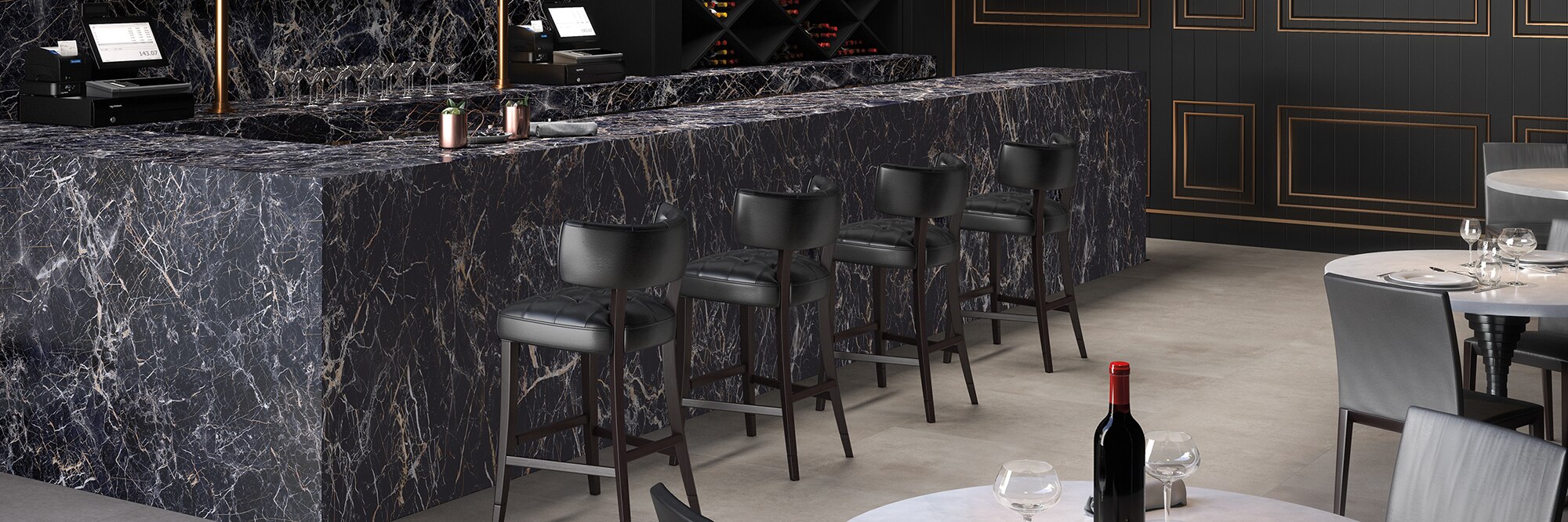 Restaurant bar with black with white veining porcelain slab on the wall, bar top and front, and gray stone look flooring tiles.