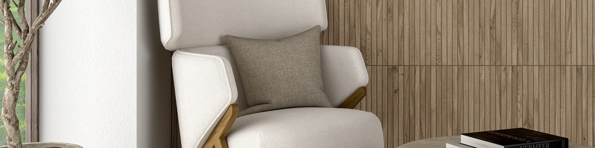 Reading nook with wall tile that looks like wood slates, off-white cushioned chair with gray pillow, stone coffee table holding books. 