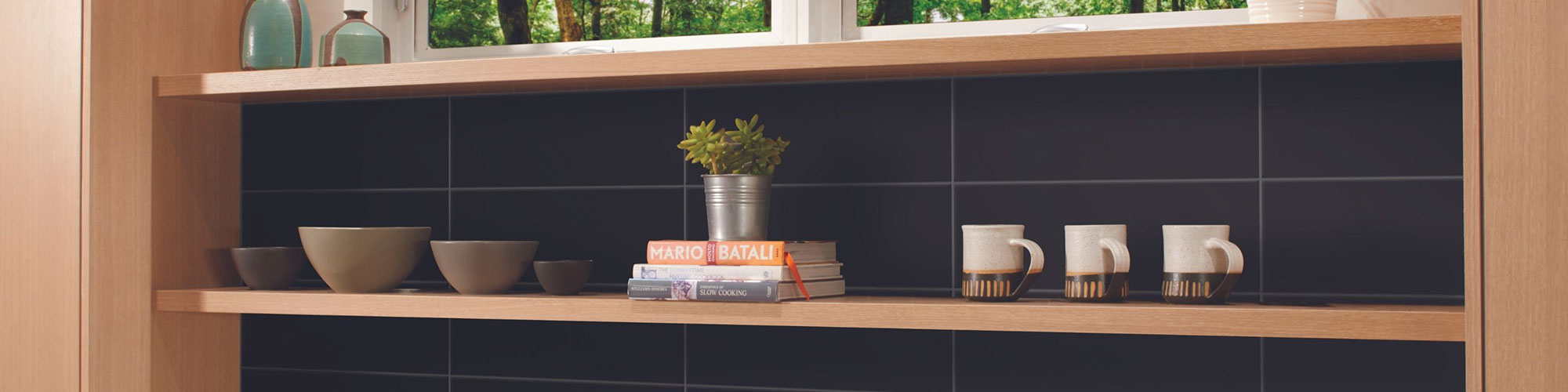 Kitchen cabinets with open shelves, black tile backsplash, bowls, cups, and a small potted plant.