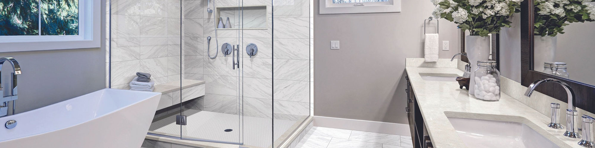 Bathroom with white & gray veining floor and shower tile that looks like marble, shower with bench and frameless glass walls, and free-standing soaker tub.